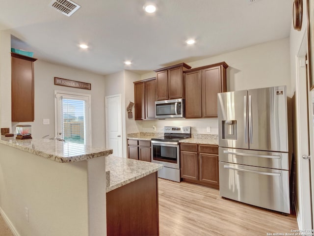 kitchen featuring light stone counters, light wood-type flooring, kitchen peninsula, and appliances with stainless steel finishes