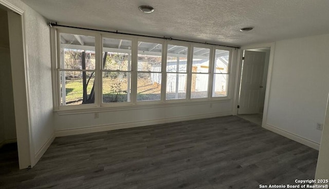 empty room featuring dark wood-type flooring and a textured ceiling