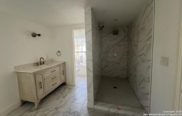 bathroom featuring tiled shower, vanity, toilet, and a textured ceiling