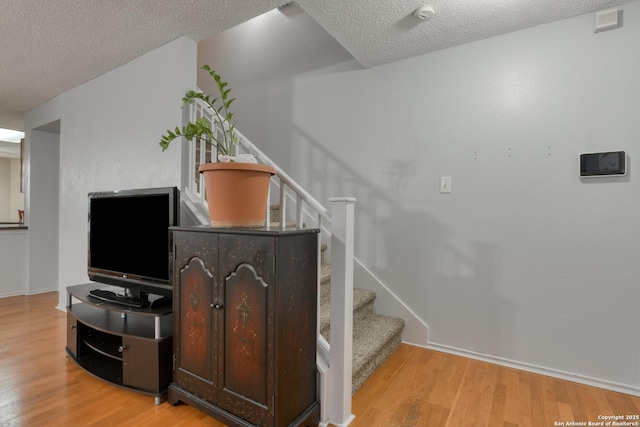 stairs featuring wood-type flooring and a textured ceiling