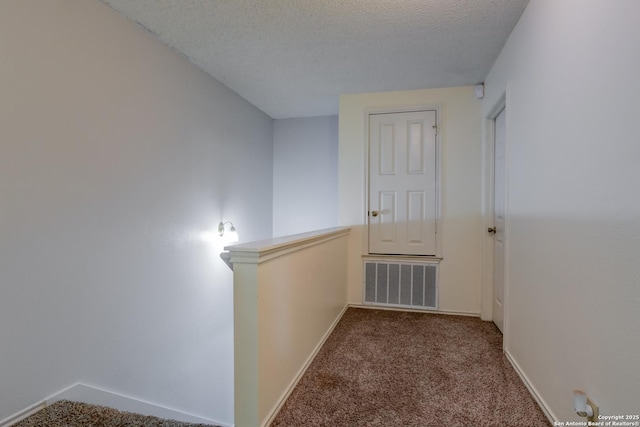 corridor with carpet floors and a textured ceiling