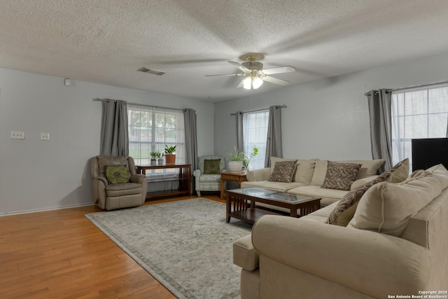 living room featuring ceiling fan, light hardwood / wood-style flooring, and a textured ceiling