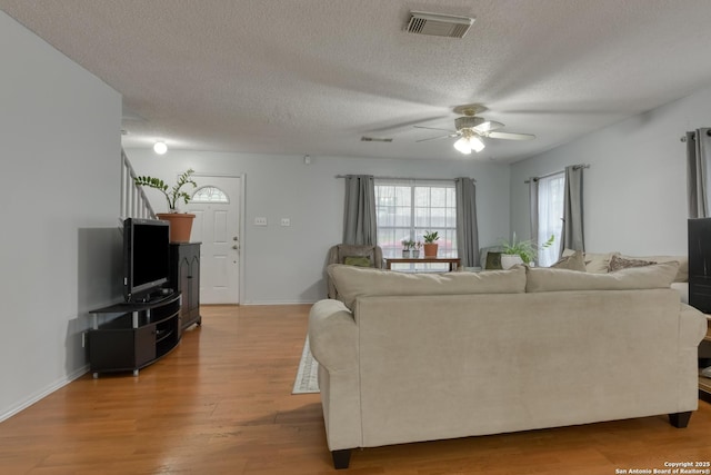 living room featuring hardwood / wood-style flooring, ceiling fan, and a textured ceiling