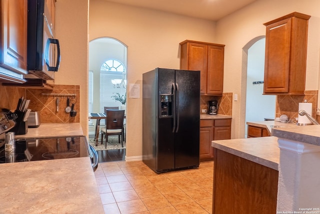 kitchen with tasteful backsplash, light tile patterned flooring, black refrigerator with ice dispenser, and electric range oven