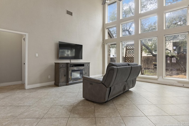 living room with a towering ceiling, light tile patterned floors, and a wealth of natural light