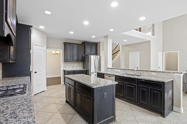 kitchen with sink, stainless steel appliances, a center island, light stone countertops, and decorative backsplash