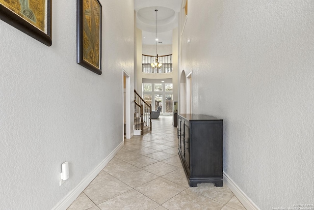 corridor featuring a high ceiling, light tile patterned floors, and a chandelier