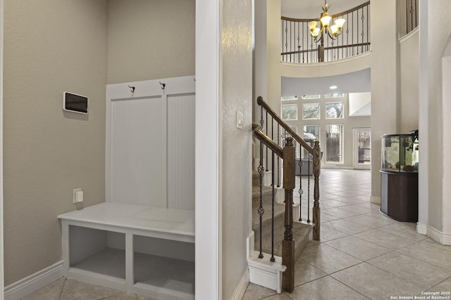 mudroom featuring a towering ceiling, a chandelier, and tile patterned flooring