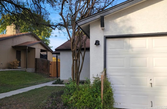 view of side of property featuring a garage and a lawn