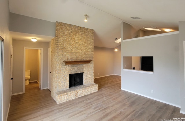 unfurnished living room featuring lofted ceiling, a fireplace, and wood-type flooring