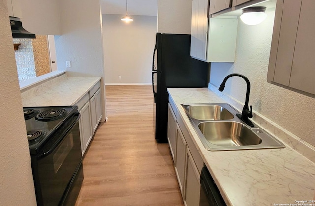 kitchen featuring sink, decorative light fixtures, ventilation hood, light wood-type flooring, and black appliances