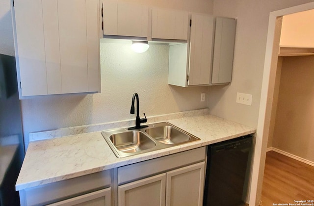 kitchen featuring wood-type flooring, black dishwasher, and sink