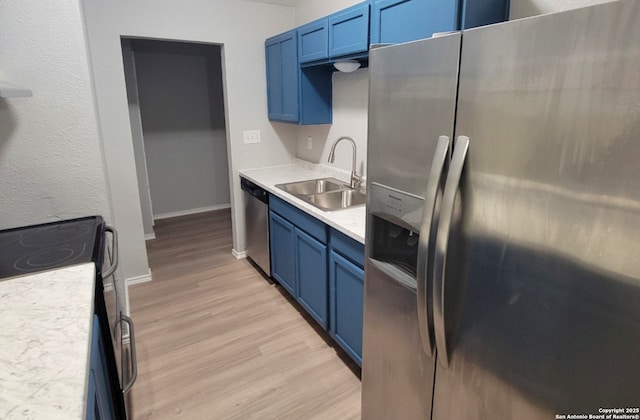 kitchen featuring stainless steel appliances, sink, blue cabinets, and light wood-type flooring