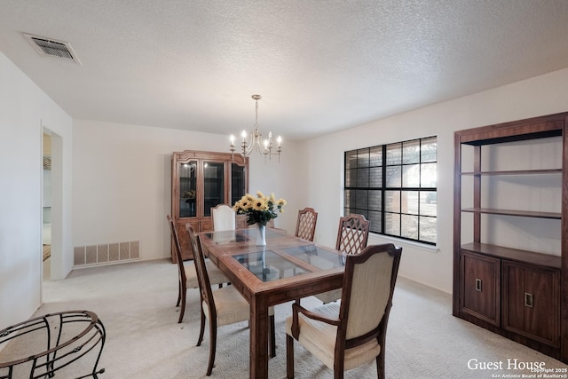 dining room with light colored carpet, a textured ceiling, and a chandelier