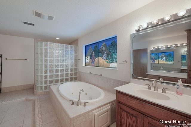 bathroom with vanity, tiled tub, and tile patterned flooring