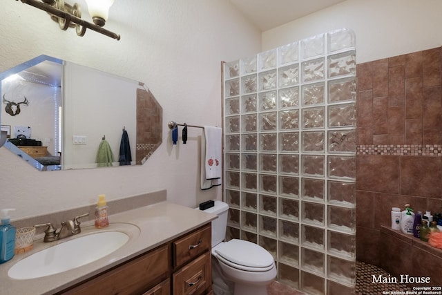 bathroom featuring vanity, tiled shower, and toilet