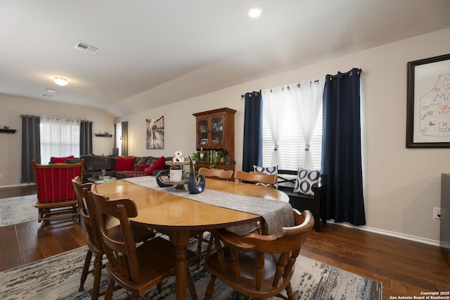 dining area featuring lofted ceiling and dark hardwood / wood-style floors