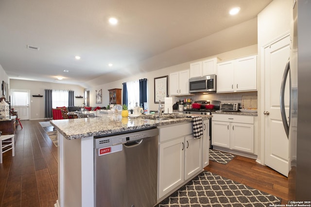 kitchen featuring stainless steel appliances, dark hardwood / wood-style floors, a center island with sink, and white cabinets