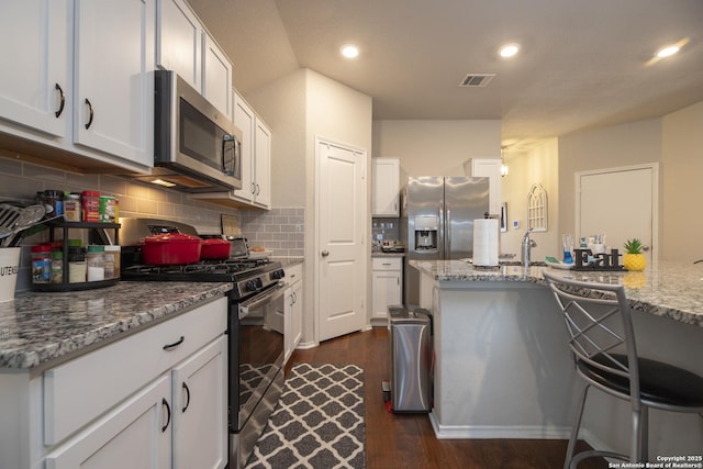 kitchen featuring light stone counters, stainless steel appliances, dark hardwood / wood-style flooring, and white cabinets