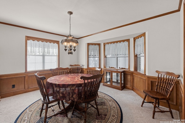 dining area with crown molding, a chandelier, and light carpet