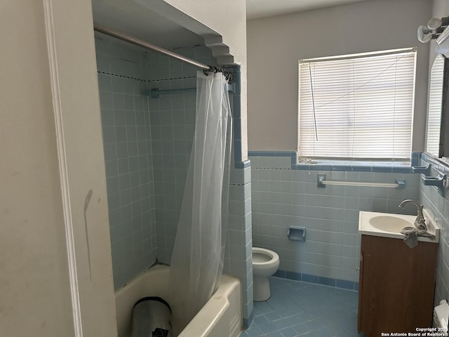 full bathroom with shower / tub combo with curtain, tile patterned flooring, tile walls, vanity, and toilet