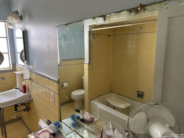 full bathroom with tiled shower / bath combo, tile walls, tile patterned floors, and toilet