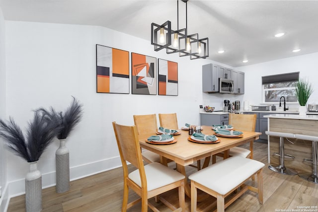 dining space featuring hardwood / wood-style flooring, vaulted ceiling, and sink