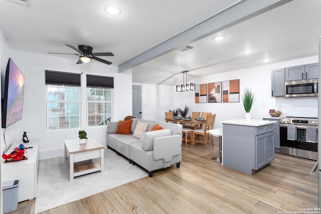 living room featuring beamed ceiling, ceiling fan, a textured ceiling, and light wood-type flooring