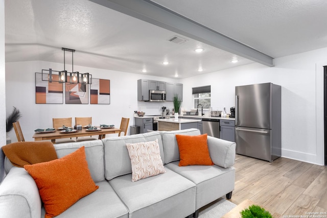 living room with beam ceiling, light hardwood / wood-style floors, and a textured ceiling