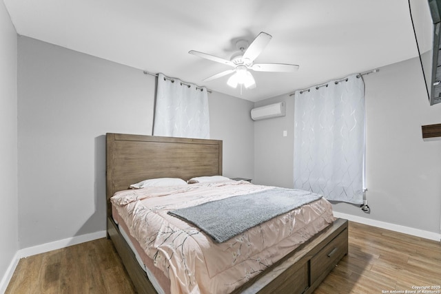 bedroom featuring ceiling fan, hardwood / wood-style floors, and a wall unit AC