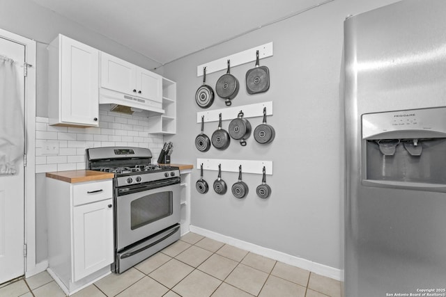 kitchen with butcher block counters, tasteful backsplash, light tile patterned floors, stainless steel range with gas stovetop, and white cabinets