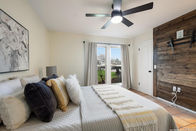 bedroom with ceiling fan, light tile patterned floors, and wooden walls