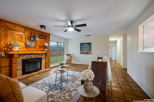 living room featuring dark tile patterned flooring, a fireplace, and ceiling fan