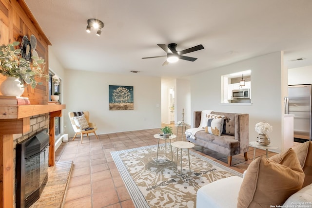 living room with a brick fireplace, light tile patterned floors, and ceiling fan