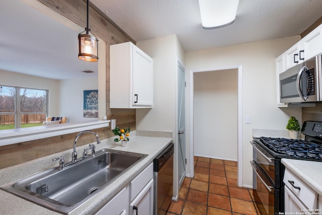 kitchen with sink, appliances with stainless steel finishes, white cabinetry, a textured ceiling, and decorative light fixtures