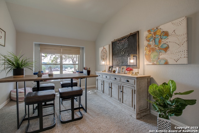 dining room featuring lofted ceiling and light carpet