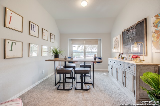 dining area with lofted ceiling and light carpet