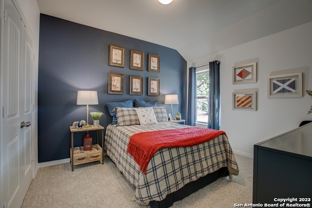 bedroom with light carpet and lofted ceiling