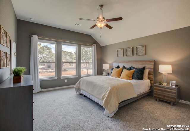 bedroom with vaulted ceiling, light colored carpet, and ceiling fan