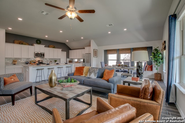 living room with ceiling fan, lofted ceiling, and light hardwood / wood-style flooring