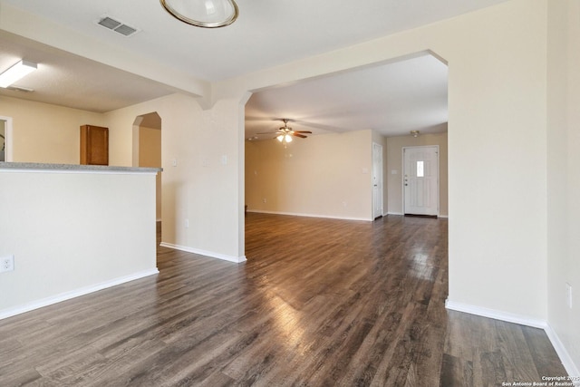 unfurnished living room with ceiling fan, dark hardwood / wood-style flooring, and beam ceiling