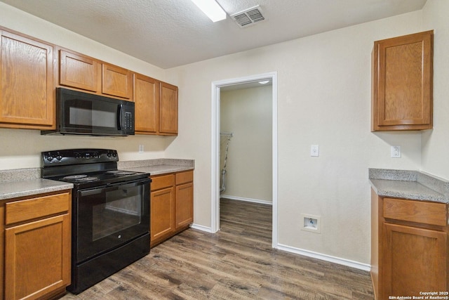 kitchen with dark hardwood / wood-style floors, a textured ceiling, and black appliances