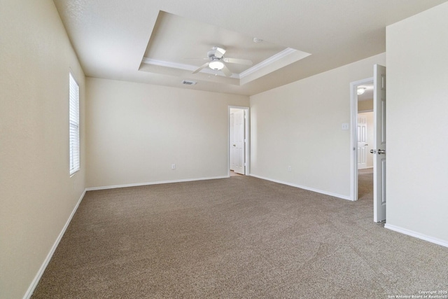 spare room with crown molding, ceiling fan, a raised ceiling, and carpet