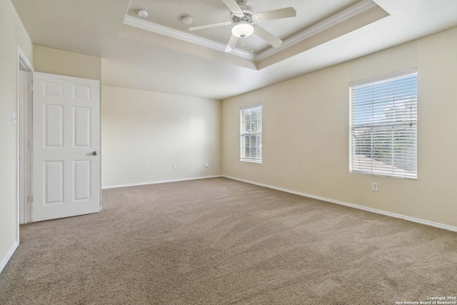 empty room featuring carpet floors, ornamental molding, a raised ceiling, and ceiling fan