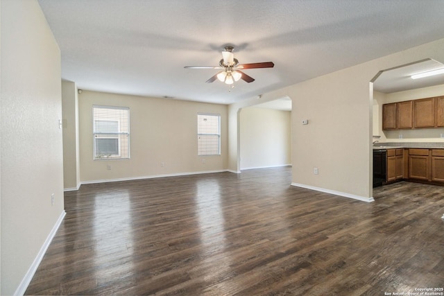 unfurnished living room featuring dark wood-type flooring, ceiling fan, and a textured ceiling