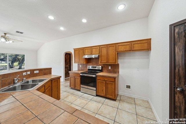 kitchen with vaulted ceiling, tile countertops, tasteful backsplash, sink, and electric stove