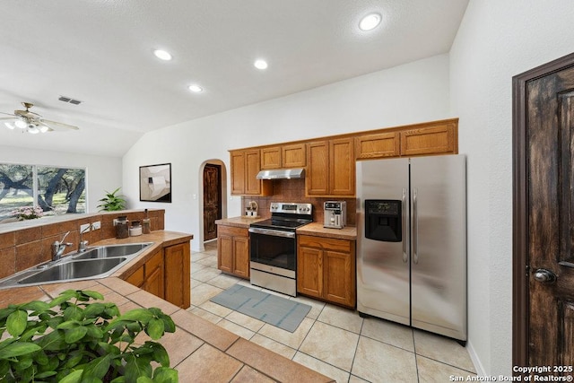 kitchen featuring sink, light tile patterned floors, stainless steel appliances, tasteful backsplash, and vaulted ceiling