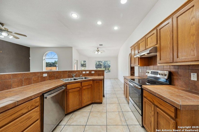 kitchen featuring sink, light tile patterned floors, tile counters, and appliances with stainless steel finishes