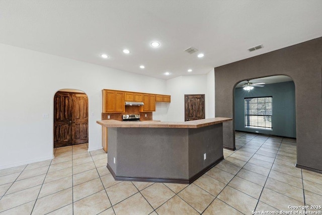 kitchen with light tile patterned flooring, stainless steel range oven, and a kitchen island