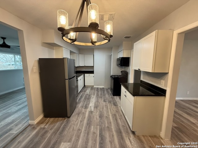 kitchen featuring ceiling fan with notable chandelier, white cabinets, dark hardwood / wood-style flooring, hanging light fixtures, and black appliances